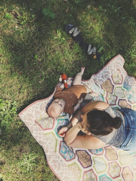 Amanda Davis, DPT, PRPC and baby Sloan laying on colorful quilt in grass