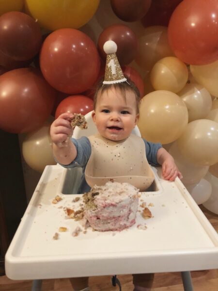 Baby in first birthday hat with cake