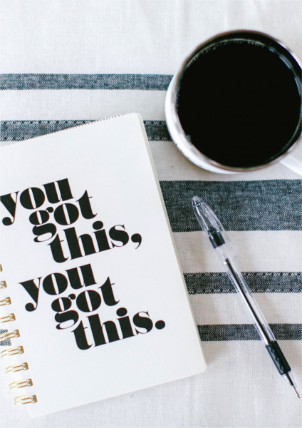 Coffee cup next to journal on blue and white cloth