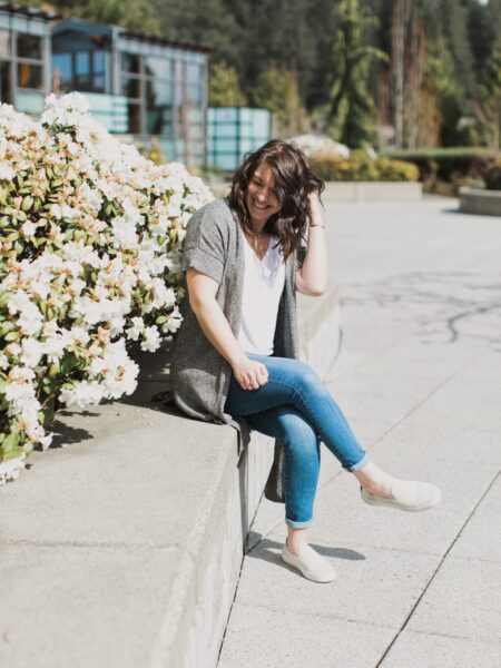 Dr. Amanda Davis of Make + Manifest sitting near flowers in jeans and white t-shirt