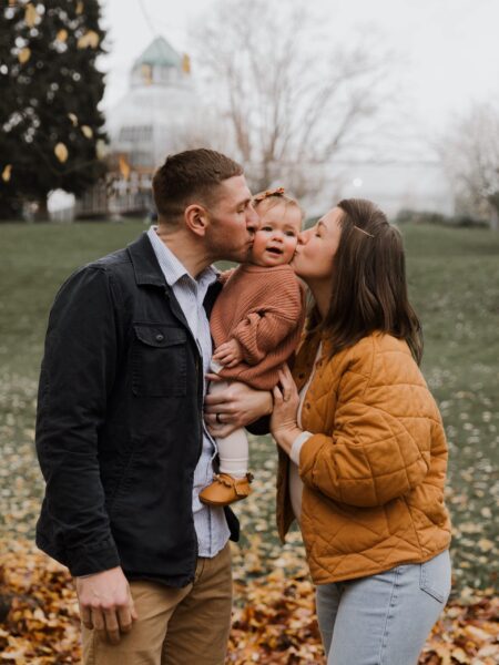 Dad and mom kissing baby’s cheeks