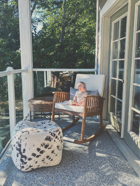 Baby sitting on rocking chair on porch in summer