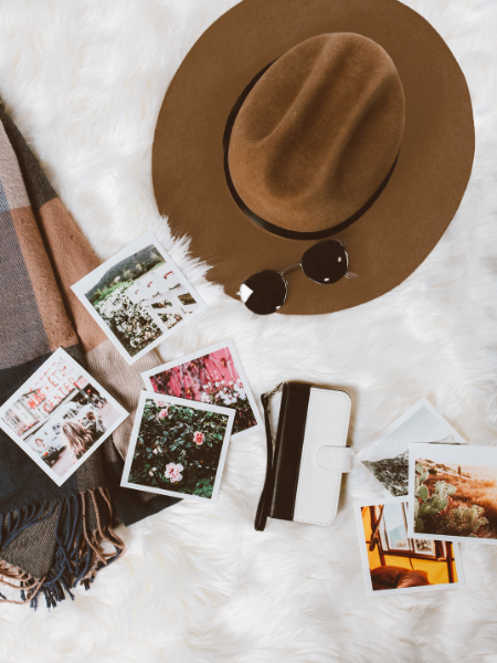 flat lay of smartphone, hat, sunglasses, and pictures