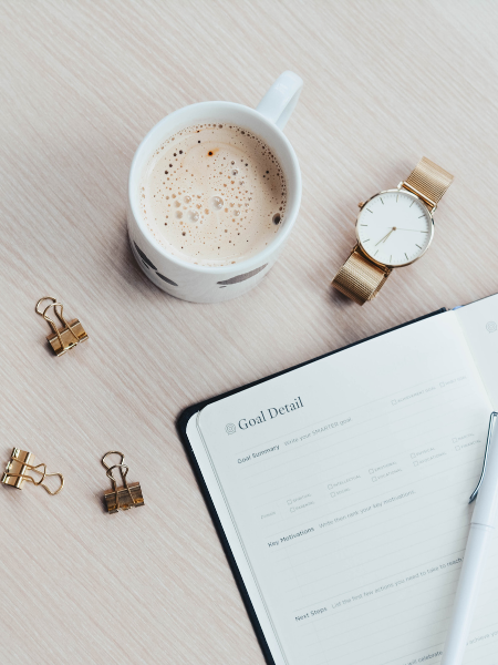 Flat lay with planner, cup or coffee, paper clips, and watch