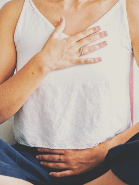 Woman with hand on chest deep breathing for pelvic health