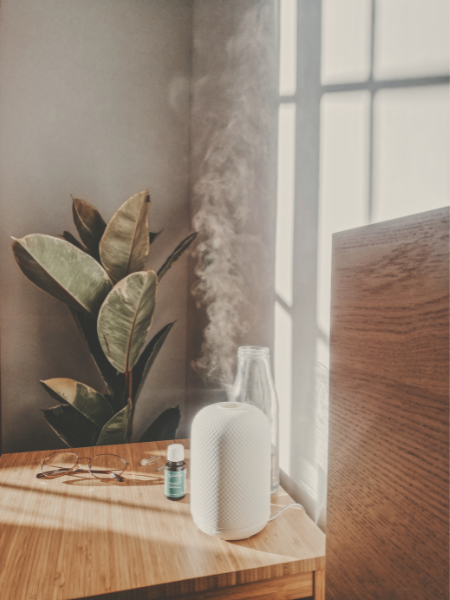 Diffuser, bluelight glasses, essential oils, and water on nightstand for a woman’s better night sleep