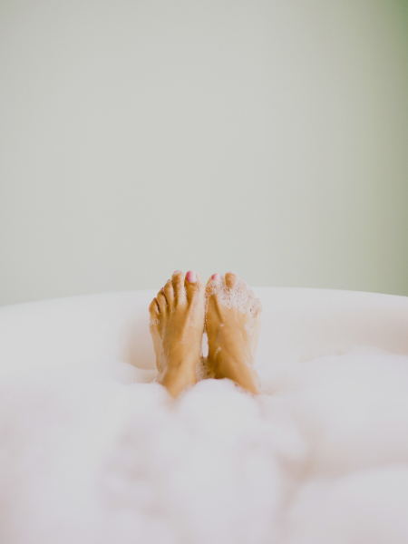 women’s feet in bubble bath for weekend reset