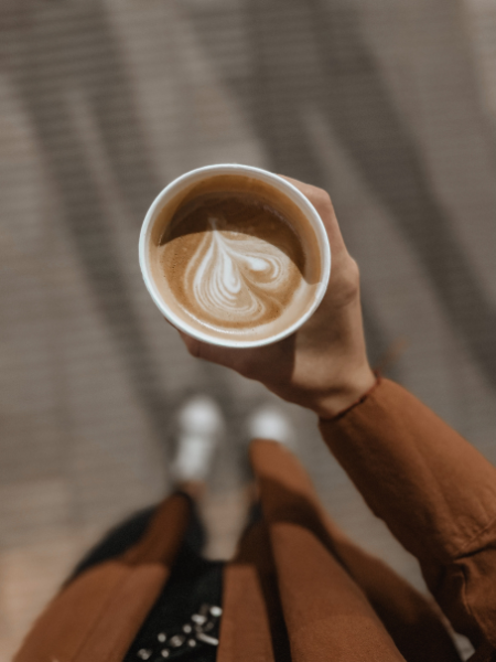 woman holding warm morning drink with latte art