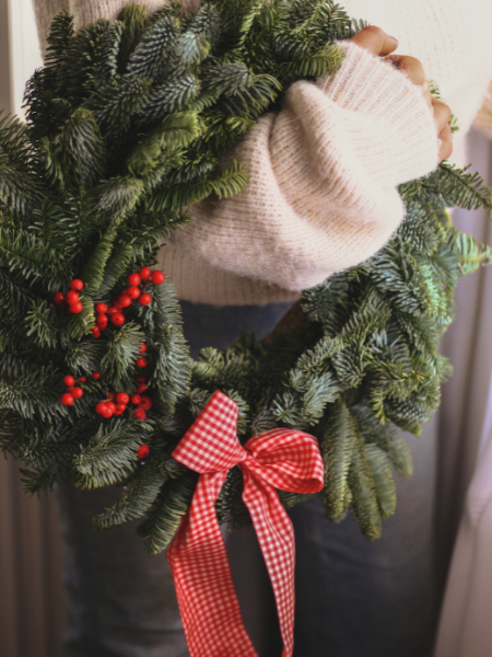 woman holding wreath with red bow